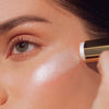 Roen Beauty Roglow Skin Stick Highlighter – Glazed showing model putting product on cheek