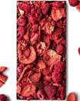 Berry Berry Chocolate (85 g) shown unwrapped with dried strawberry and raspberry pieces in the background