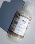 R+Co Ring Tone Curl Cream showing bottle laying on back with shadow