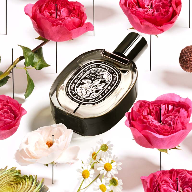 Diptyque Eau Rose De Parfum another angle of  bottle laying flat with flowers 