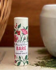 Stewart & Claire Bare Unscented Lip Balm with Rosehip Seed Oil showing on a book with a basket next to it