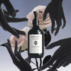 Lifestyle shot of Botanical Body Wash – Head of Roses (500 ml) with pink roses and hands in the background
