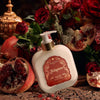 Santa Maria Novella Melograno Fluid Body Cream surrounded by red roses, pomegranates 