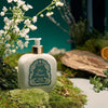 Santa Maria Novella Pot Pourri Fluid Body Cream surrounded my green moss and white flowers