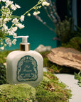 Santa Maria Novella Pot Pourri Fluid Body Cream surrounded my green moss and white flowers
