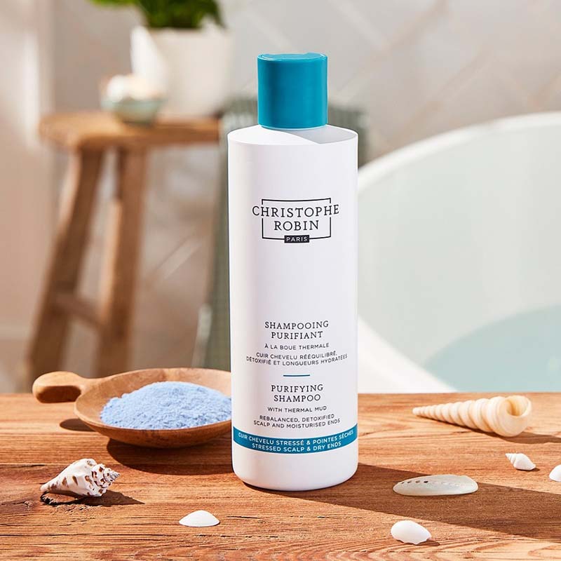 Christophe Robin Purifying Shampoo with Thermal Mud showing on counter surrounded by sea shells 