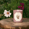 Carriere Freres Rose Pepper Candle sitting on a piece of wood in front of flowers