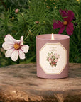 Carriere Freres Rose Pepper Candle sitting on a piece of wood in front of flowers