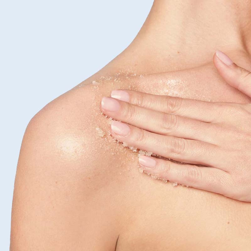 NEOM Organics Real Luxury Body Scrub showing model using scrub on chest