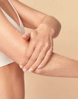 Model applying Neom Organics Great Day Body Scrub to elbow