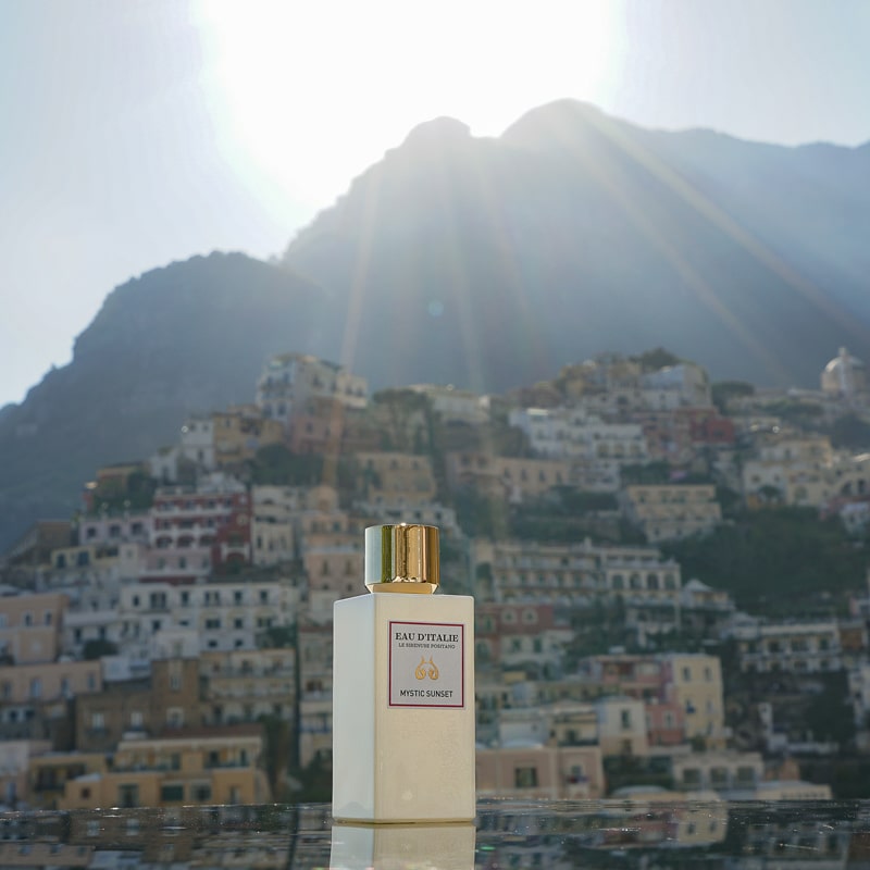 Eau d'Italie Mystic Sunset Eau de Parfum Spray (100 ml) with the Positano cliffside in the background