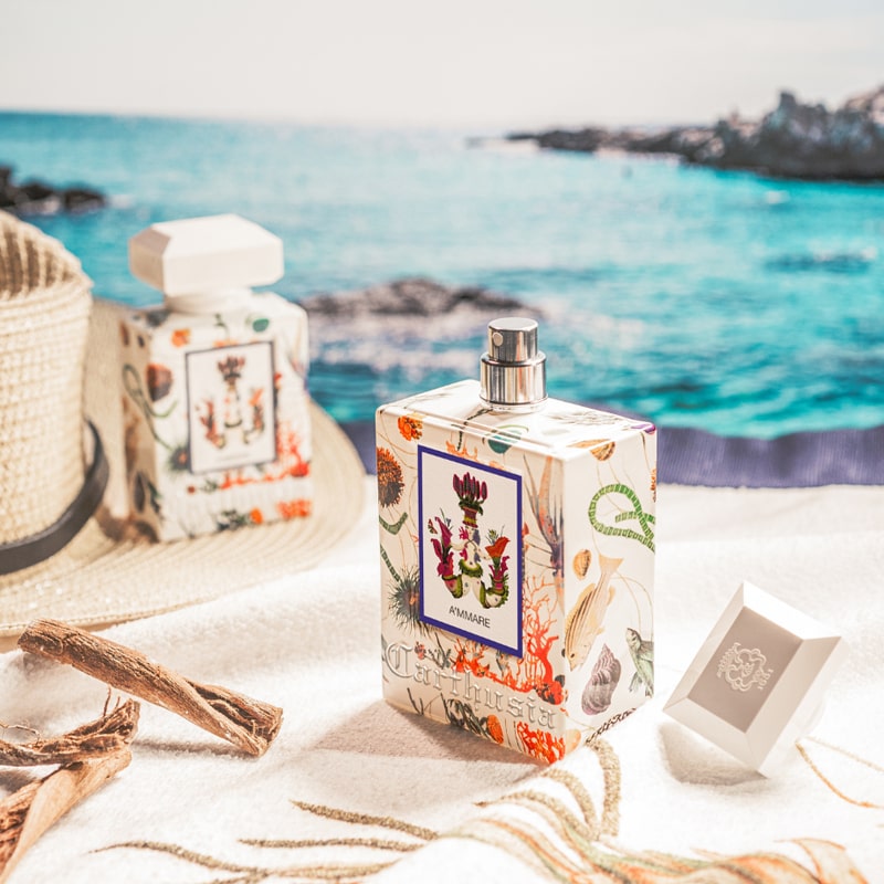 Carthusia A’mmare Eau de Parfum showing both sized parfum sitting on a towel with the ocean behind