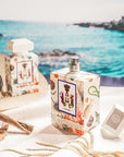 Carthusia A’mmare Eau de Parfum showing both sized parfum sitting on a towel with the ocean behind