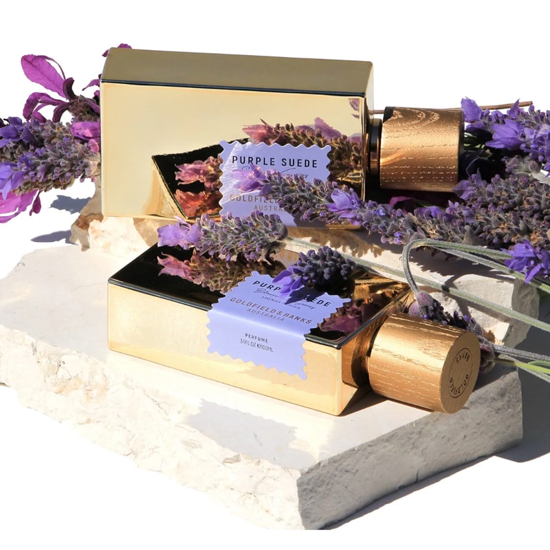 Goldfield &amp; Banks Purple Suede Perfume showing 2 bottles laying on their sides surrounded by lavender and stones