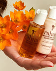 Rahua by Amazon Beauty Enchanted Island Travel Duo showing in models hand with orange flowers
