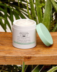 Christophe Robin Hydrating Cream Scrub sitting on wooden bench with green lid off