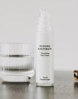 Susanne Kaufmann Nourishing Day Cream - lifestyle shot of product between a glass of water  and a hair clip