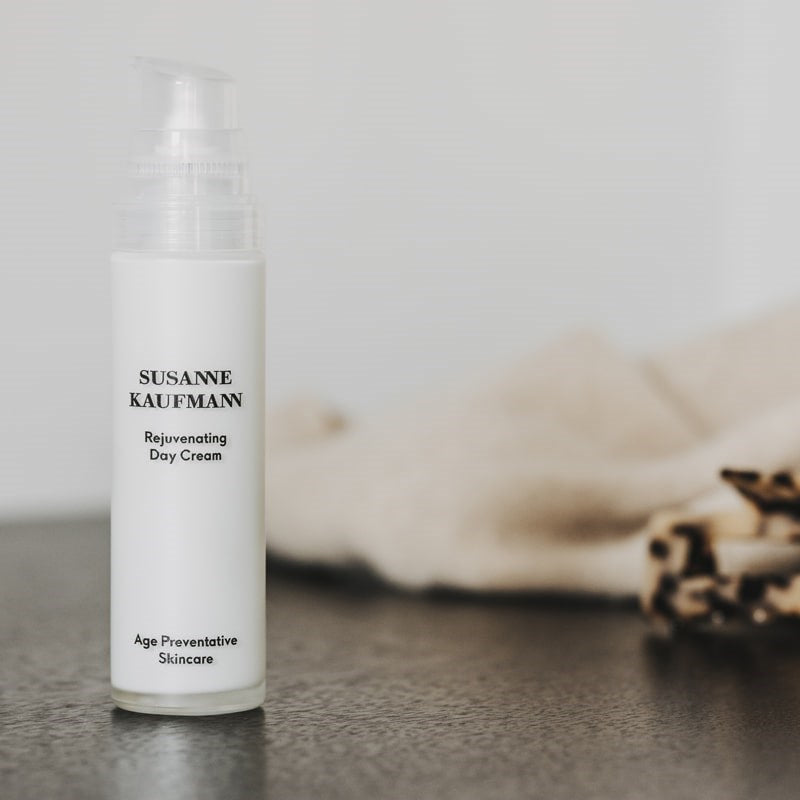 Susanne Kaufmann Rejuvenating Day Cream beauty shot of bottle on black surface with beige towel in background