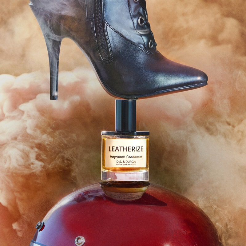 D.S. &amp; Durga Leatherize Eau de Parfum - beauty shot of bottle under a black boot and on top of a helmet