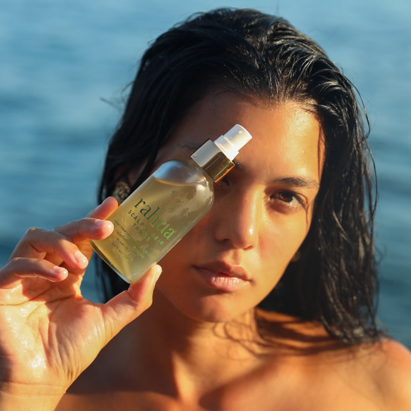 Rahua by Amazon Beauty Scalp & Skin Toner in Model's hand - ocean in background