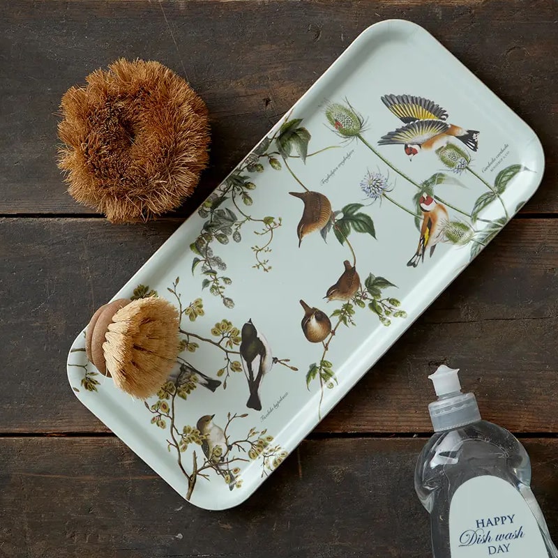 Koustrup &amp; Co. Garden Birds Serving Tray sitting on a wooden table with brush on tray and next to tray