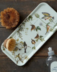 Koustrup & Co. Garden Birds Serving Tray sitting on a wooden table with brush on tray and next to tray