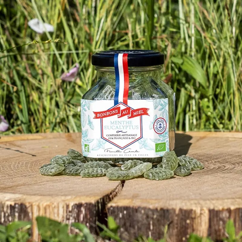 Les Abeilles de Malescot Mint &amp; Eucalyptus Honey Candies - beauty shot of jar on tree stump with candies in front of jar