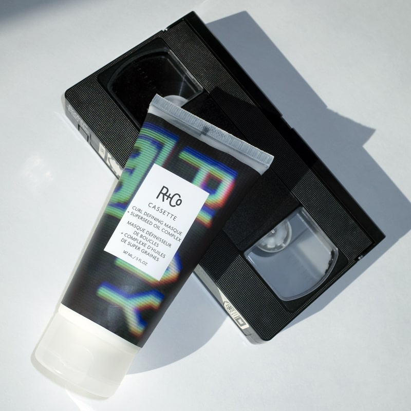 R+Co Cassette Curl Defining Masque + Superseed Oil Complex - Product shown on top of video cassette. 
