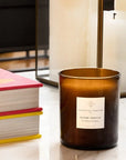 Essential Parfums Divine Vanille Scented Candle - Product displayed on table next to books