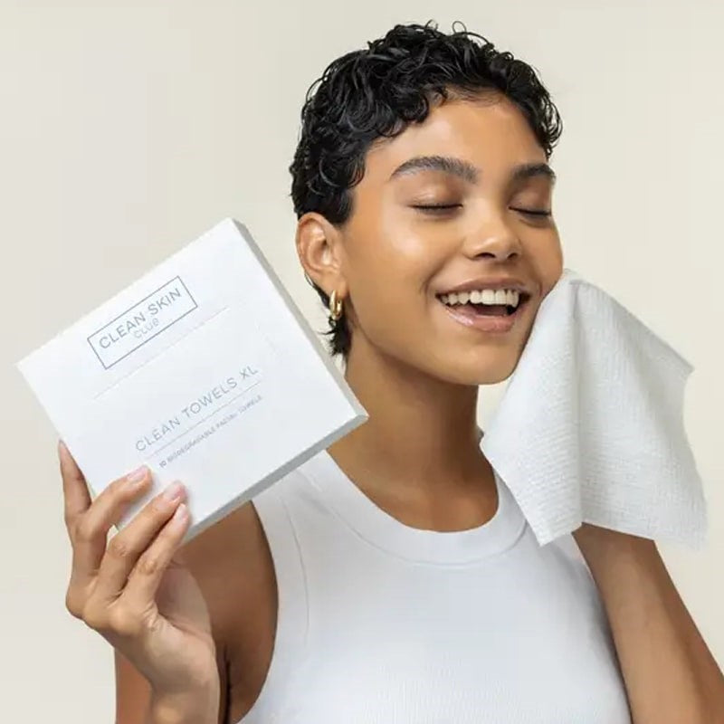 Clean Skin Club Clean Towels XL – Travel Size - Model shown wiping face with product