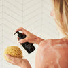 Olverum Body Cleanser - Model shown dispensing product onto loofah.