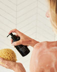 Olverum Body Cleanser - Model shown dispensing product onto loofah.