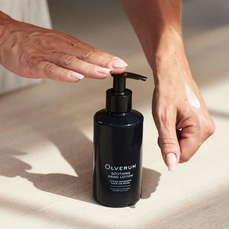 Olverum Soothing Hand Lotion - Model shown dispensing product onto hand