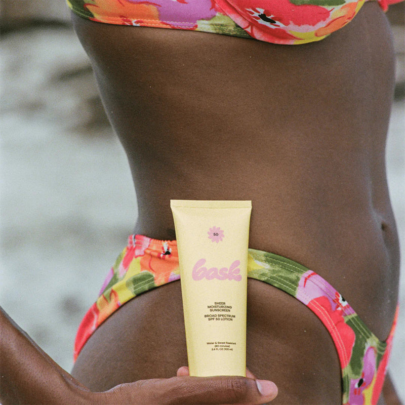 Bask Sunscreen SPF 50 Lotion Sunscreen - Model shown holding product in front of body