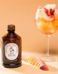 Bacanha Organic Raw Peach Syrup - Product shown next to wine glass with peach drink.