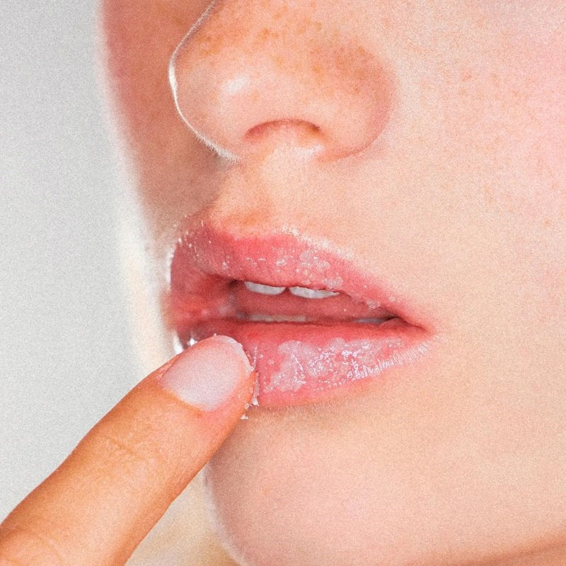 Yolaine The Lip Scrub - Closeup of model applying product to lips