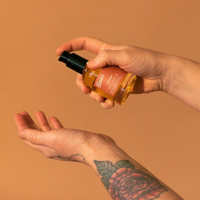 APT Herbals Rose Face + Body Oil - Model shown dispensing product into hand