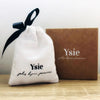 YSIE Angelique Mother-Of-Pearl Gold Plated Earrings - Product bag shown next to logo