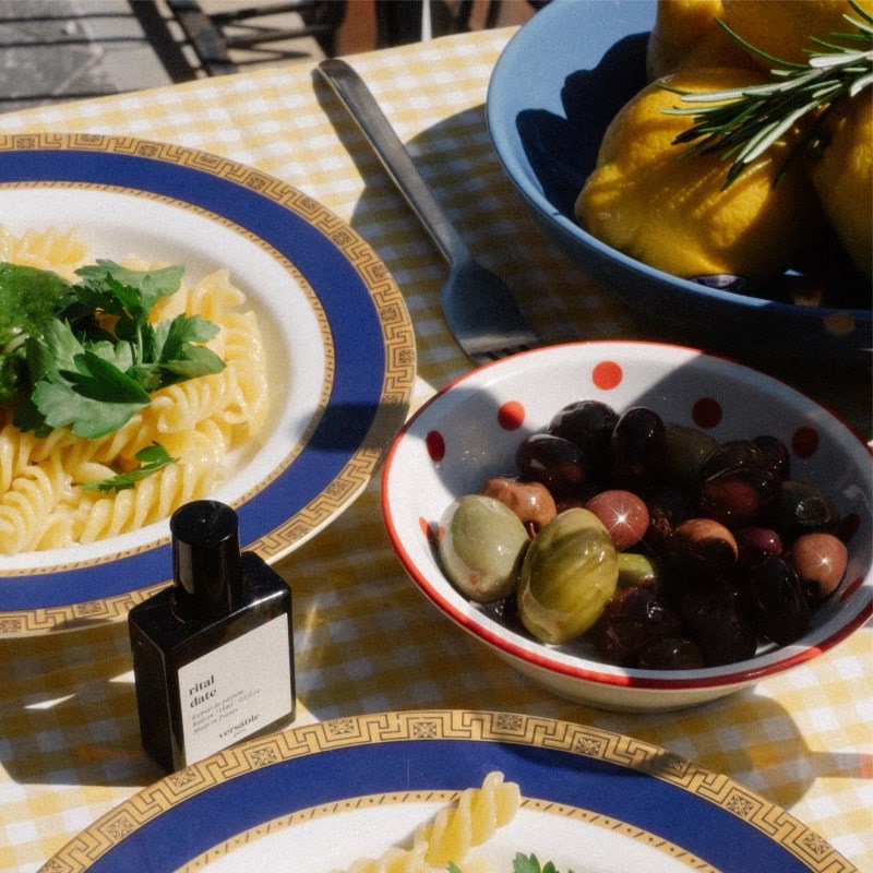 Versatile Paris Rital Date Extrait de Parfum - lifestyle photo of perfume bottle on table with plates of food