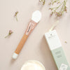 Bachca Paris Mask Applicator Brush - brush next to packaging and flowers on table