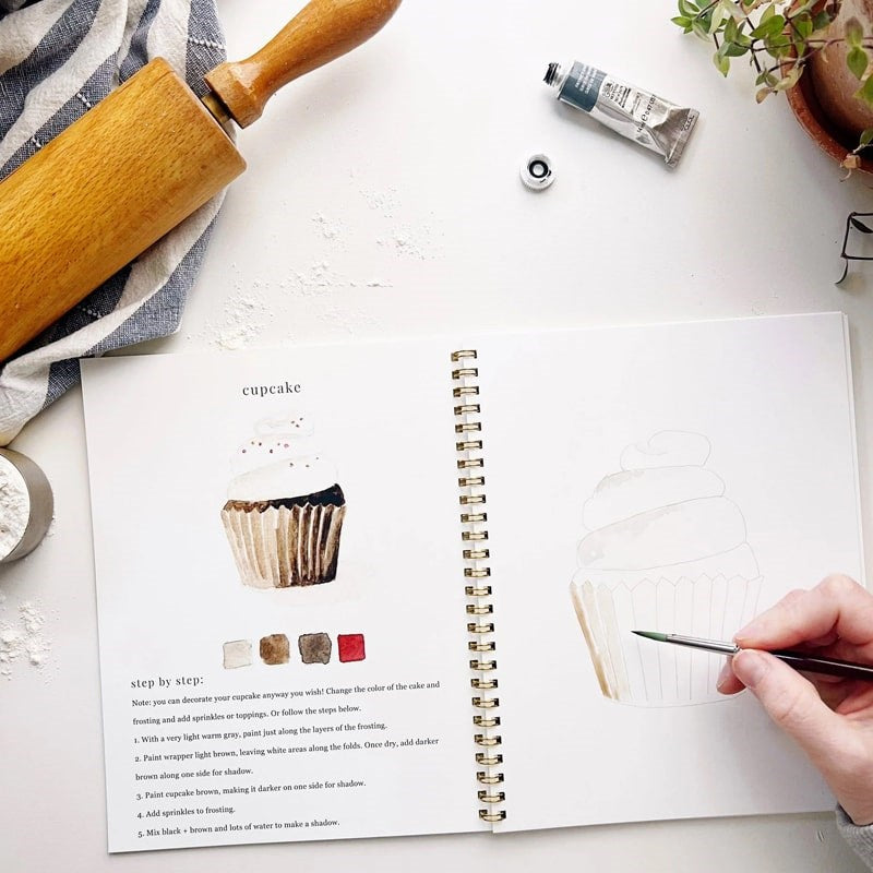 Emily Lex Studio Baking Watercolor Workbook - Model shown painting cupcake