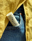 Artifact Soft Sail Smoothing Grapefruit Anise Lip Balm - Closeup of product in models pocket