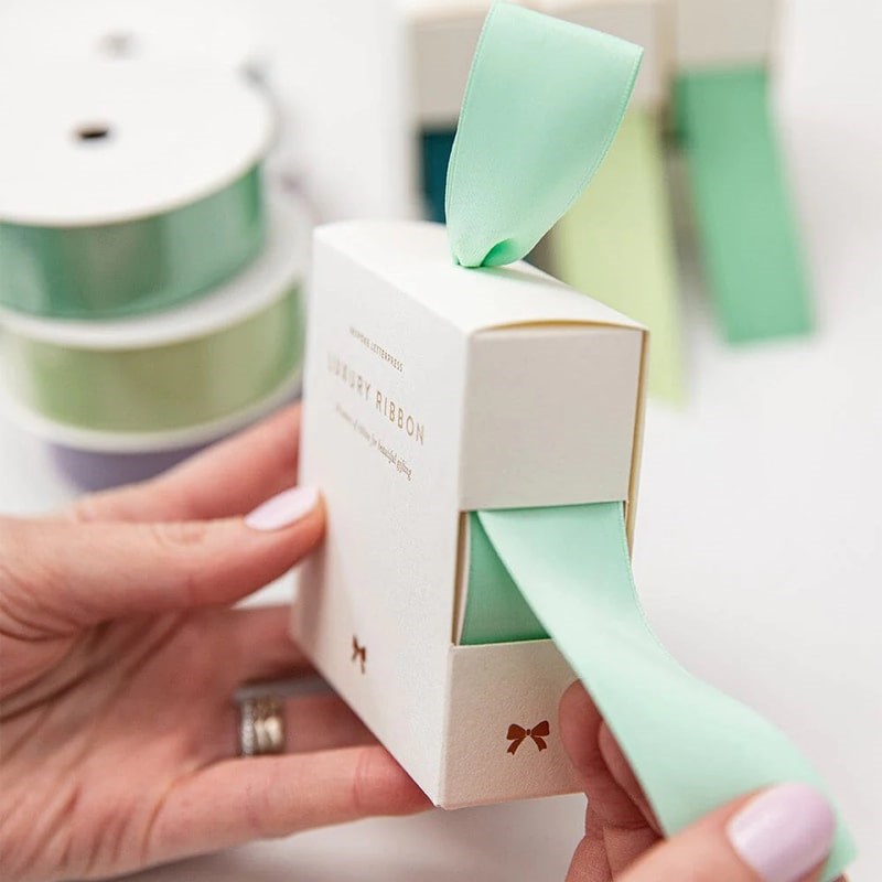 Bespoke Letterpress Mint Luxury Satin Ribbon - Model holding ribbon box pulling ribbon out