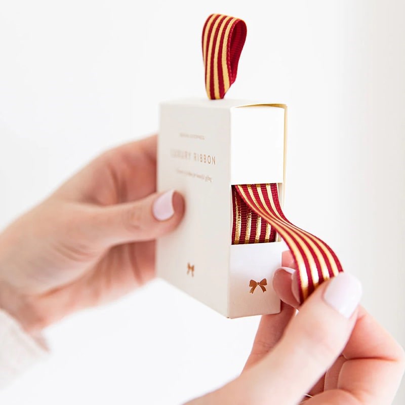 Bespoke Letterpress Red Gold Foil Striped Ribbon - Model shown holding ribbon box pulling ribbon out