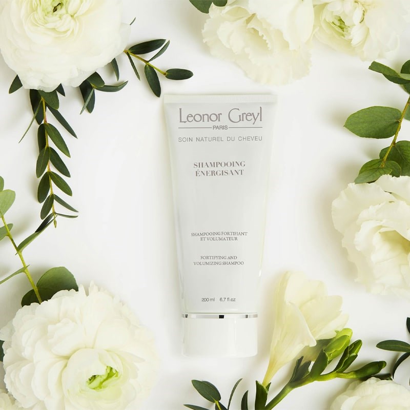 Leonor Greyl Shampooing Energisant - Fortifying and Volumizing Shampoo - Beauty shot, product shown with flowers