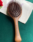The Sacred Essence Angel Scalp Massage Brush - Product shown on teal background