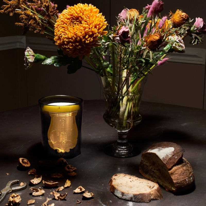 Cire Trudon Cyrnos Candle lifestyle shot with flowers in a vase in the background